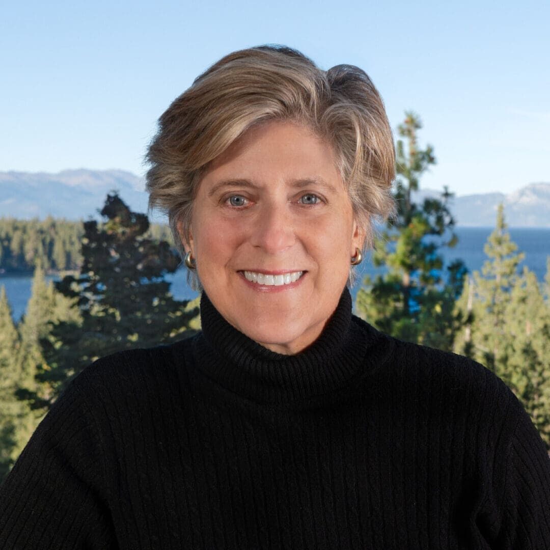 A woman in black shirt standing next to trees.